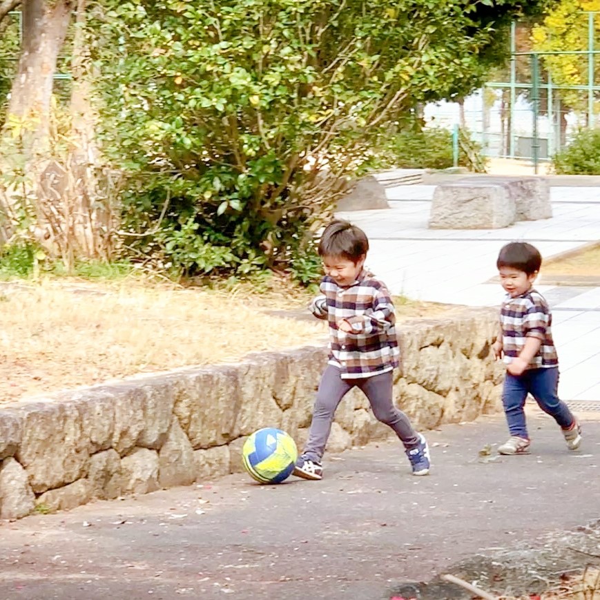 坂道でボールをドリブルする子ども