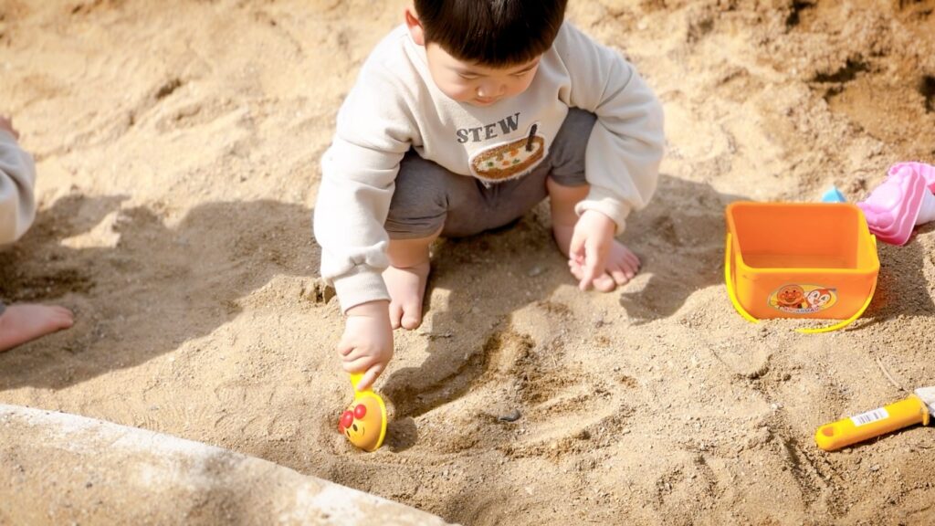 砂場遊びを楽しむ2歳児